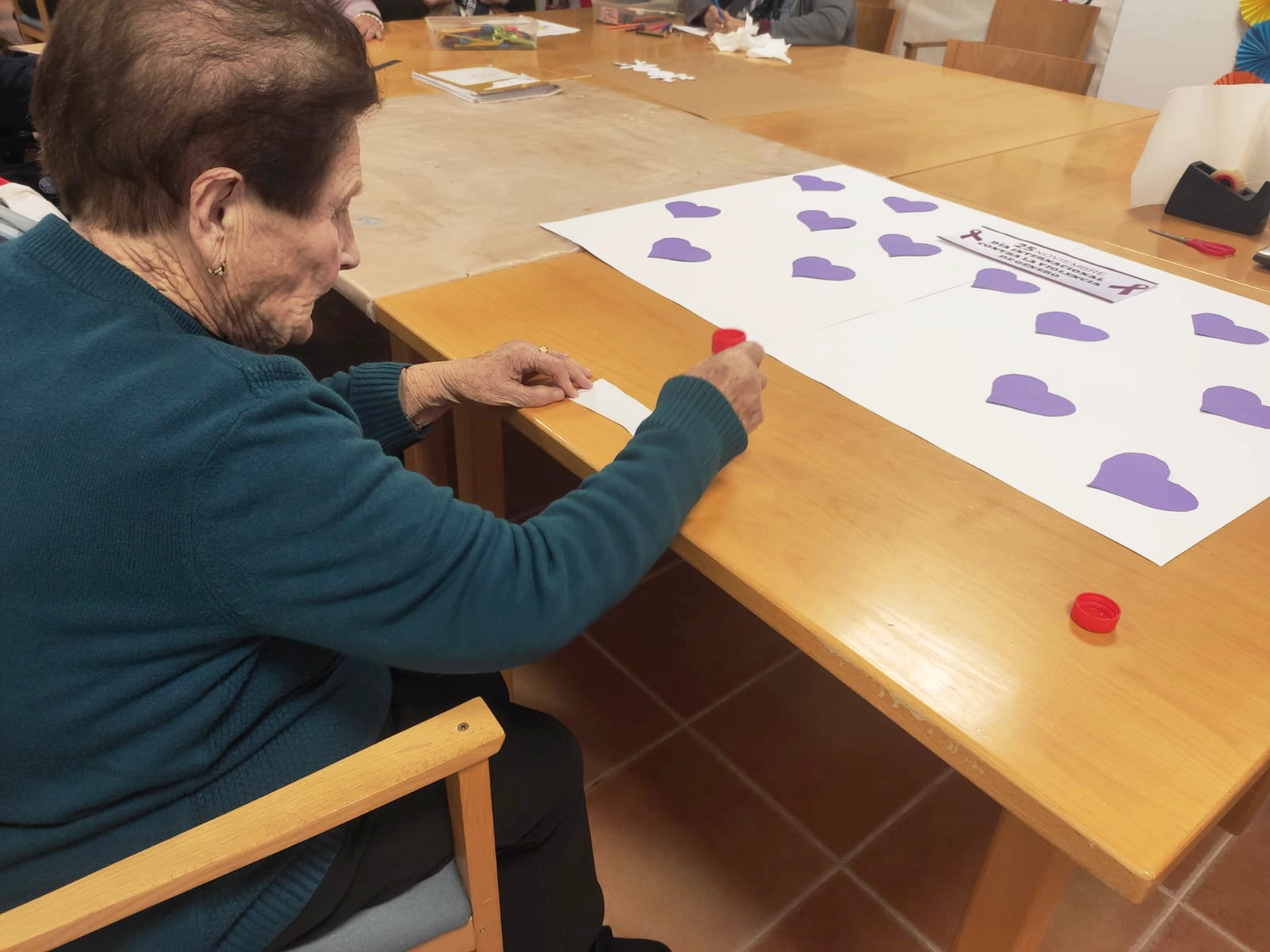 Mujer de la residencia Escoriza creando corazones morados para el cartel por el Día Contra la Violencia de Género