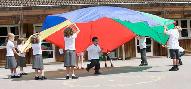Niños jugando al juego del paracaídas