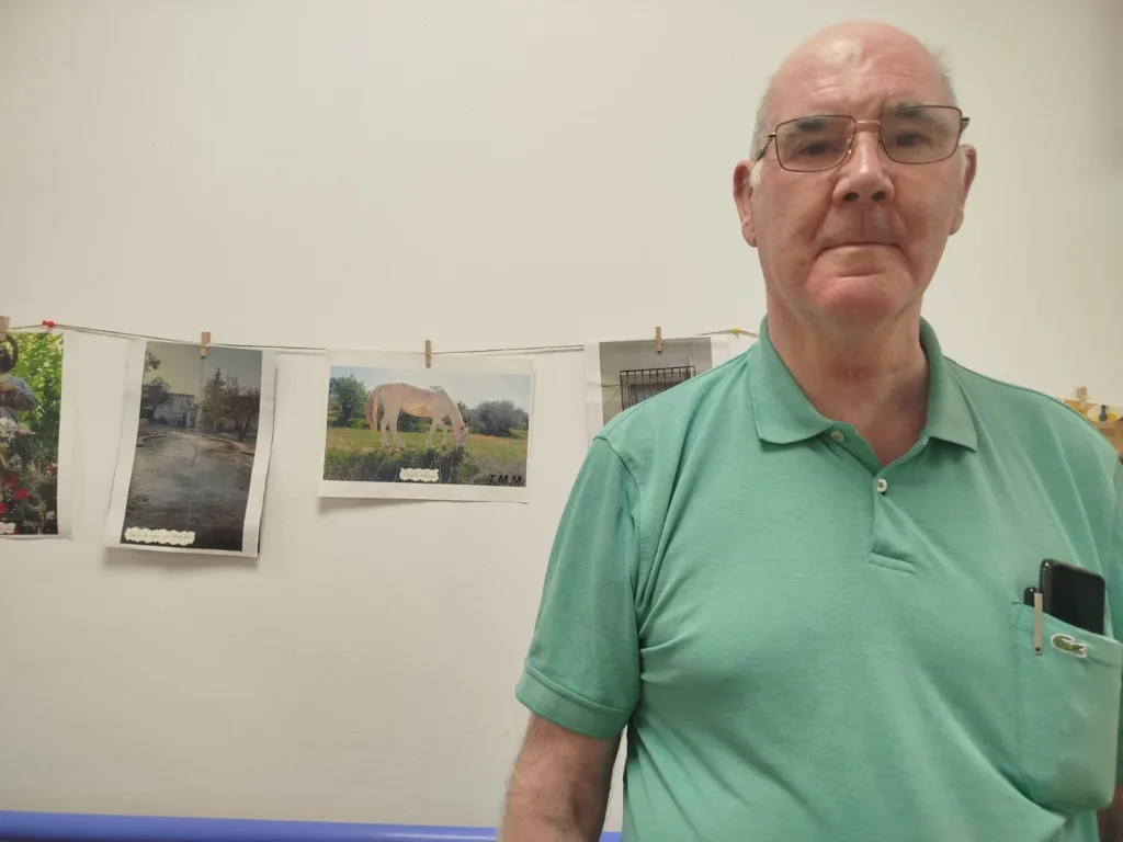 Tomñas Moreno, residente de la Residencia Escoriza, posando frente a su exposición fotográfica "Esencia de Pozo Alcón"
